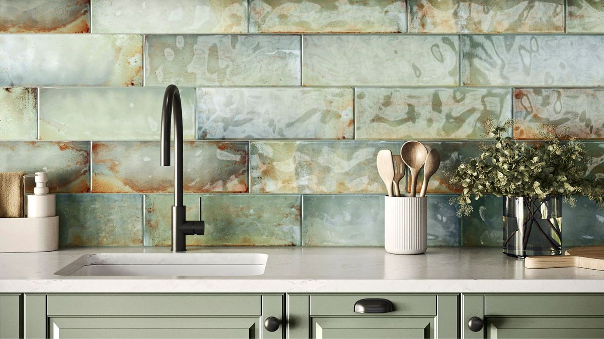 Kitchen with sage green cabinetry, a white countertop, and a black matte faucet. The backsplash features glossy, textured sage green tiles with hints of rust and blue