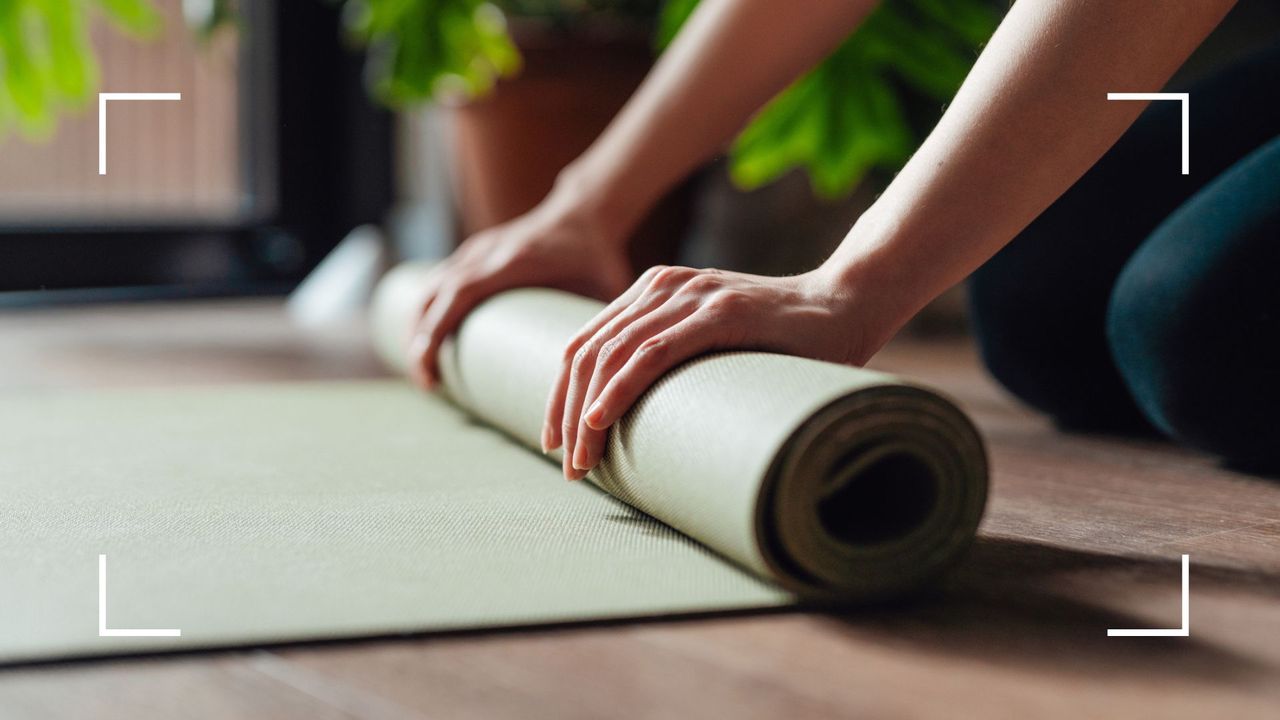 Woman&#039;s hands folding up a Pilates mat on the floor, representing a full-body Pilates workout