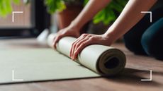 Woman's hands folding up a Pilates mat on the floor, representing a full-body Pilates workout
