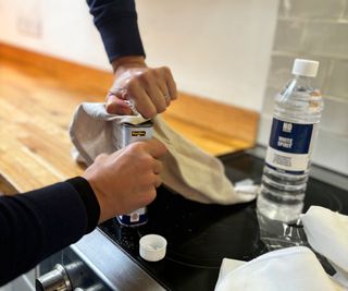 me taking lid of tin of worktop oil with a cloth around the lid for extra grip