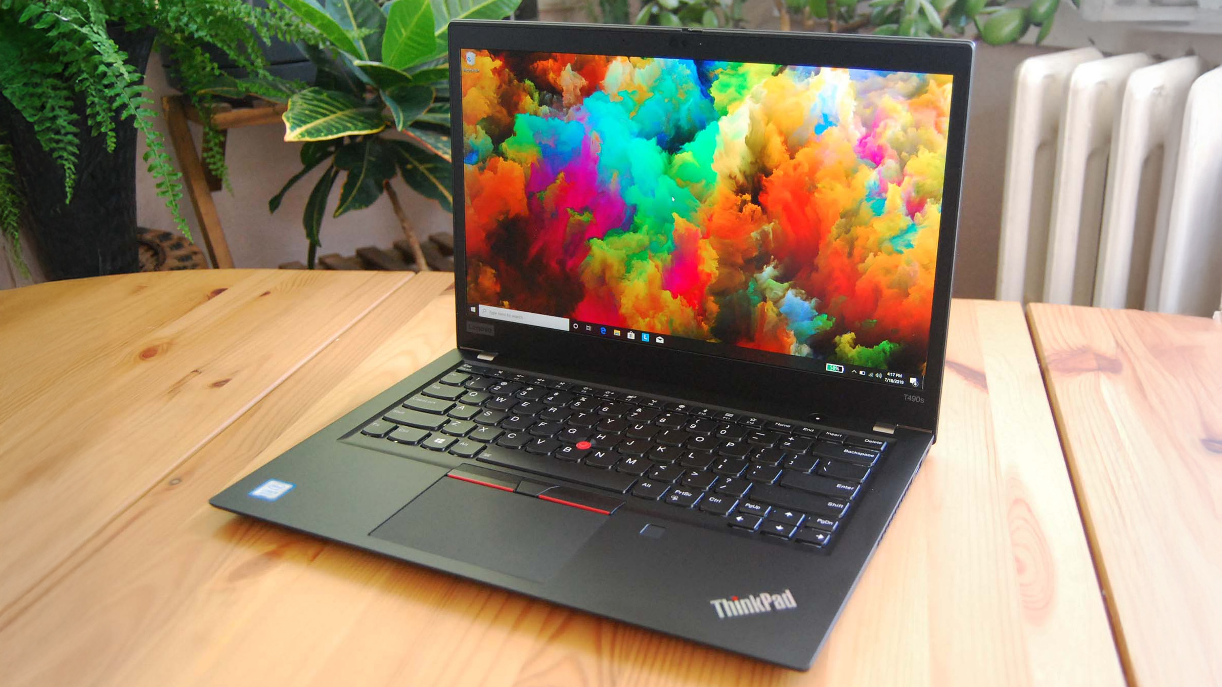 Lenovo ThinkPad T490s on a wooden desk, showing Windows 10 desktop
