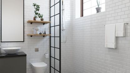 A black grid shower screen in a white tiled bathroom