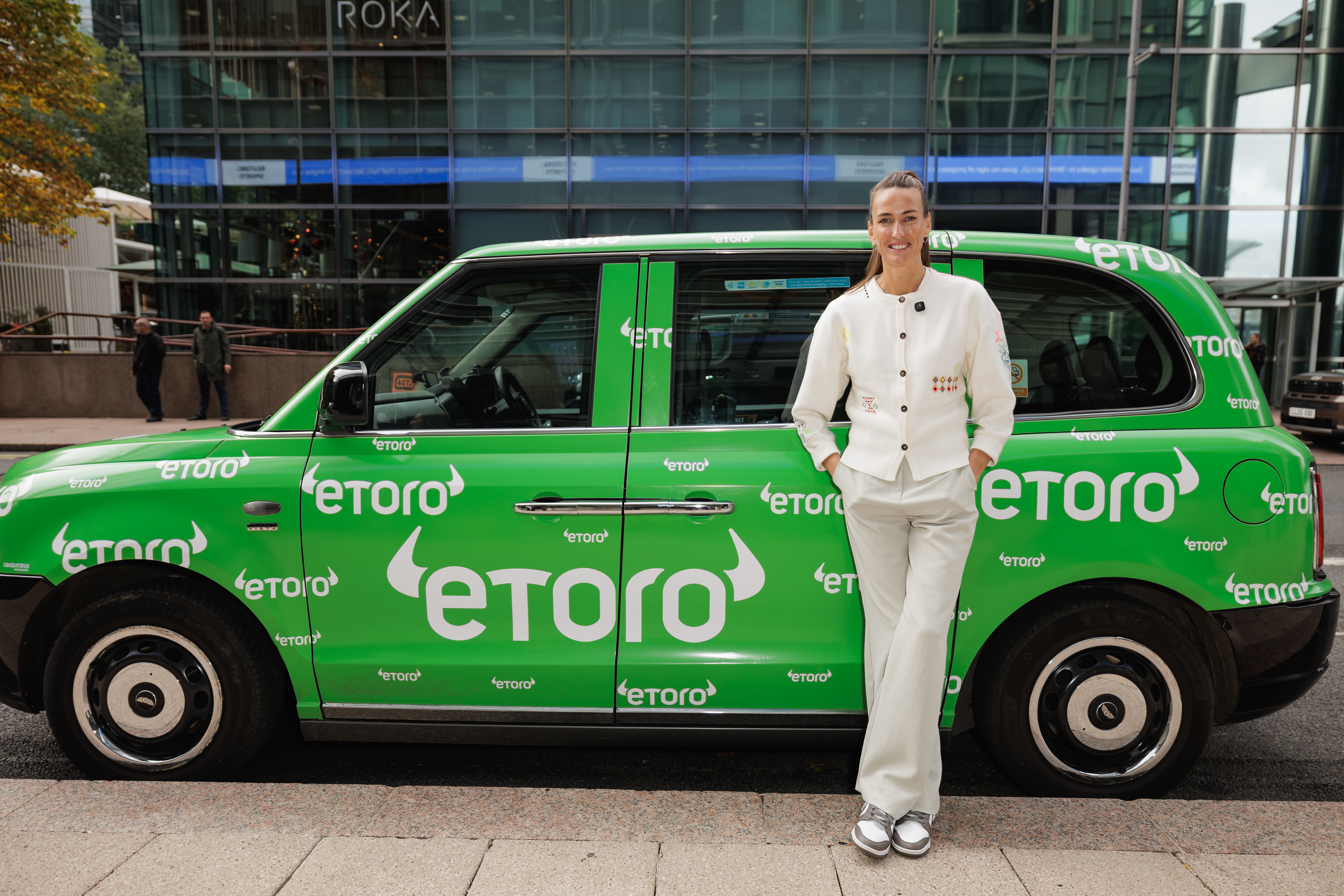 Jill Scott stands by a taxi with eToro advertising on it