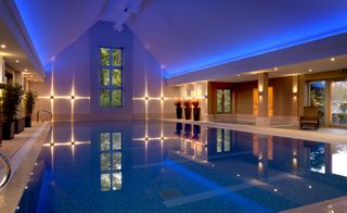 Swimming pool of the Calcot Manor, Gloucestershire, UK with wall lights and sun loungers