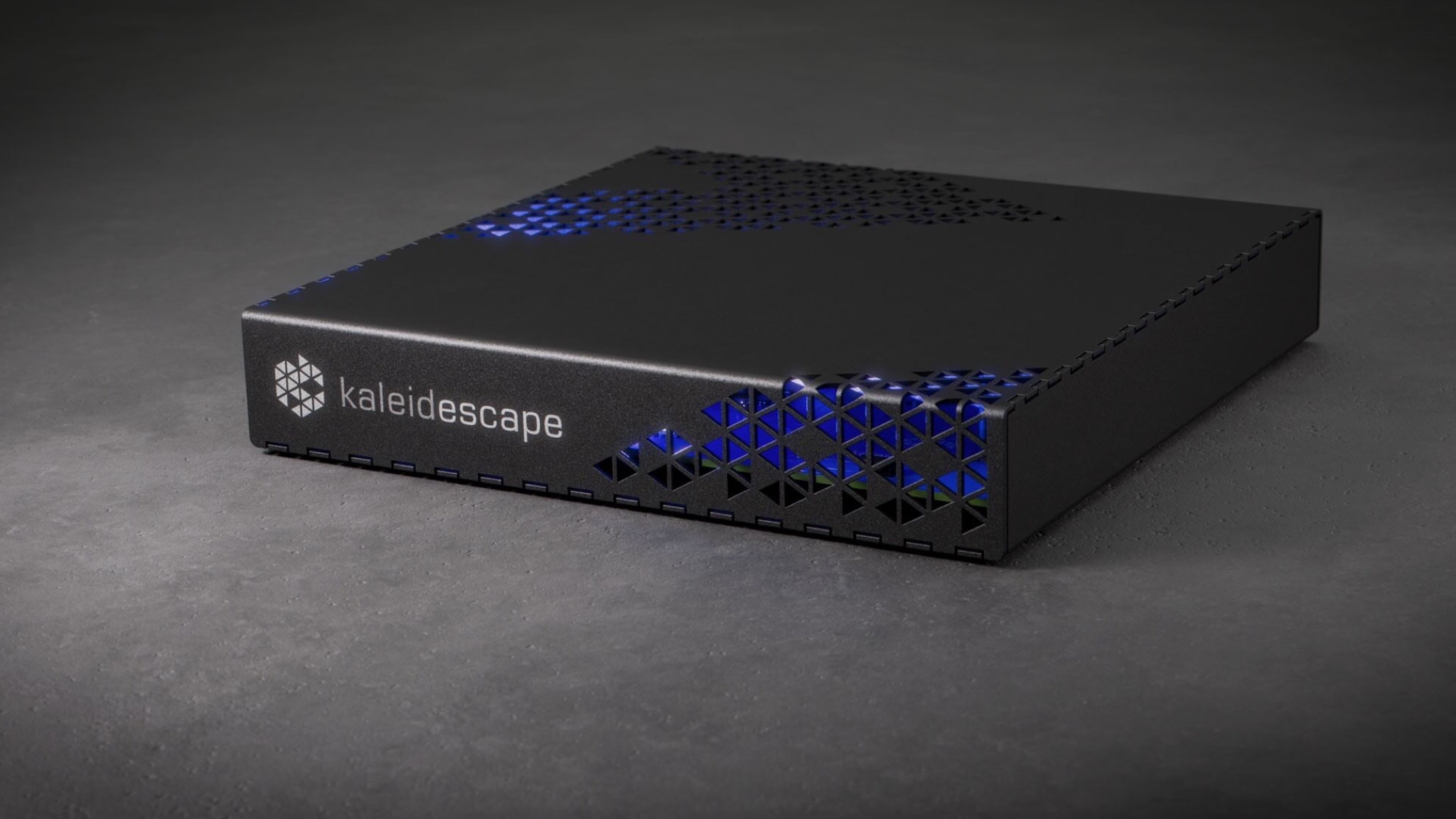 Kaleidescape Strato E Movie Player. It&#039;s a black rectangular device with blue highlighting, photographed atop a grey surface