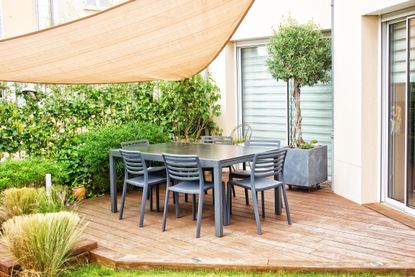 A small backyard with decking, a canopy, and some plants