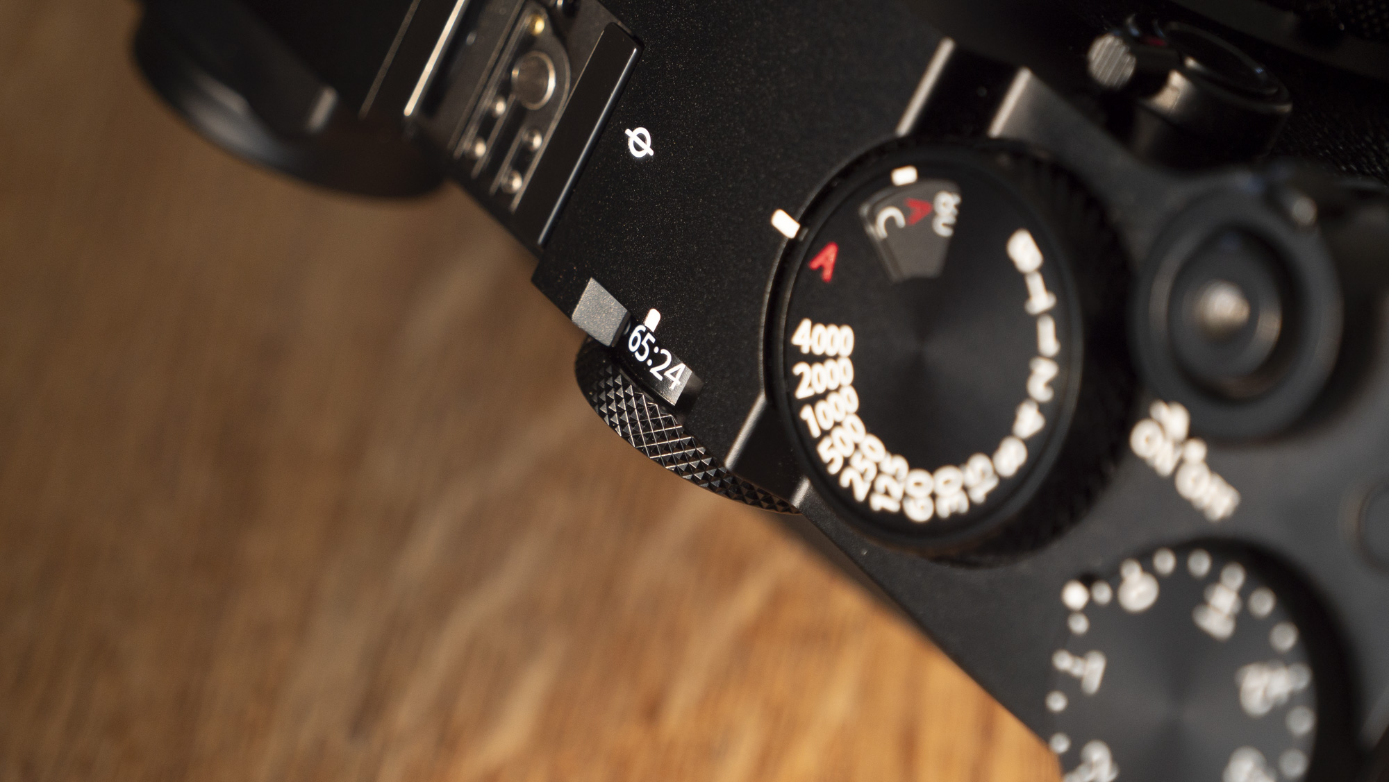 All-black Fujifilm GFX100RF rangefinder-style camera on a wooden table