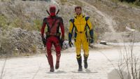 Ryan Reynolds in his red Deadpool suit and Hugh Jackman in yellow Wolverine suit walking through desert setting in Deadpool & Wolverine.