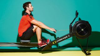 Man on a Concept2 rowing machine is in the catch position