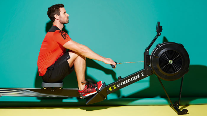 Man on a Concept2 rowing machine is in the catch position