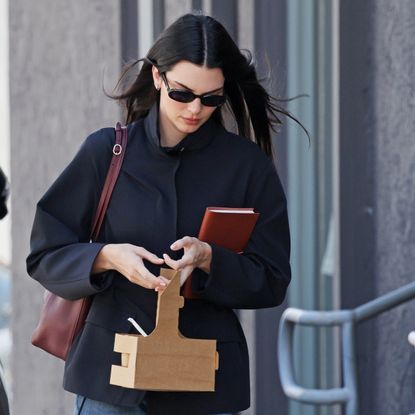 Kendall jenner wears a navy jacket with a burgundy bag.