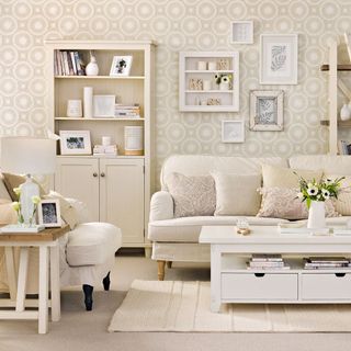 neutral living room with circle wallpaper, white sofa and armchair, white coffee table and white display unit