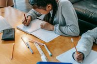 A student works with a pen and paper at a desk.