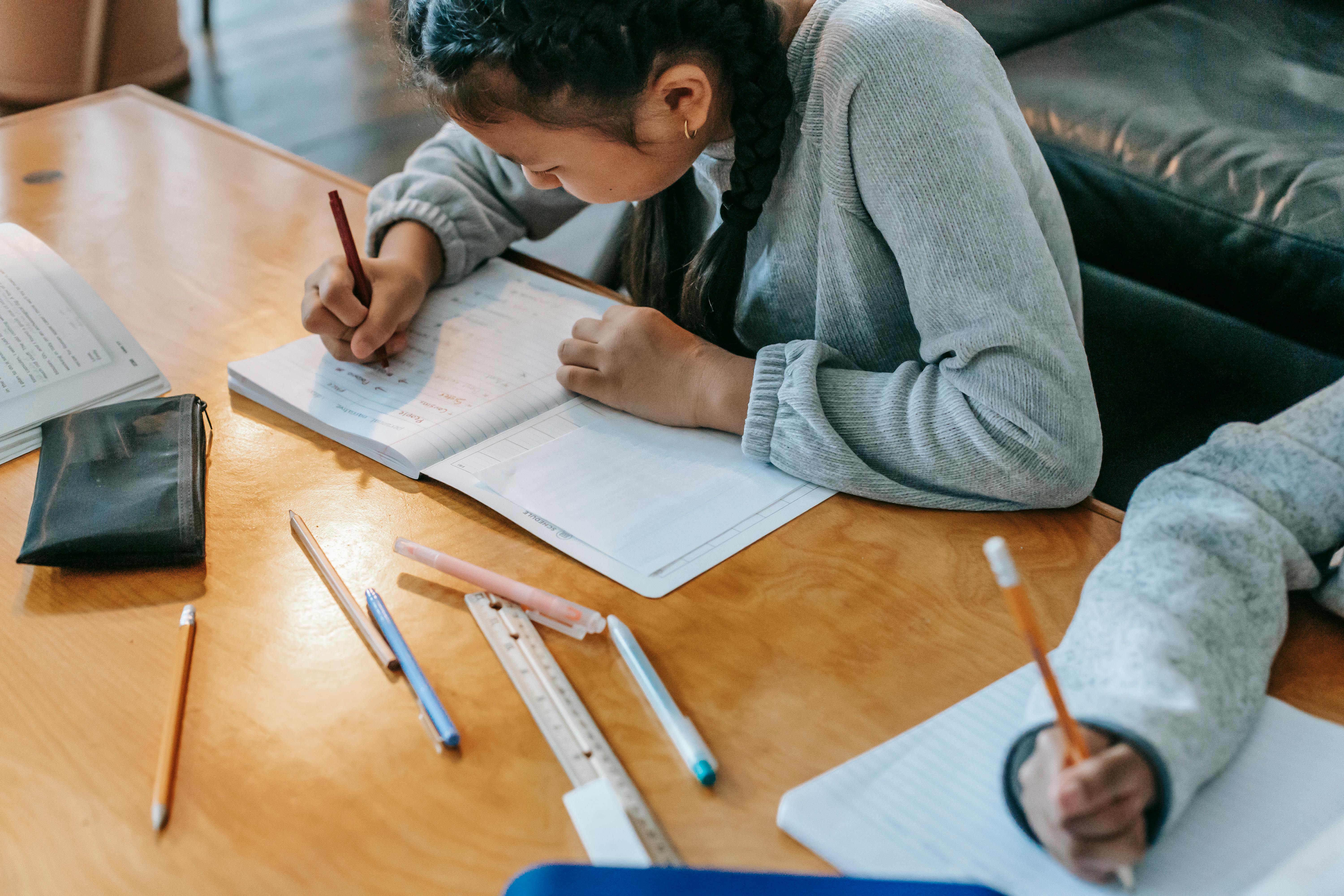 A student works with a pen and paper at a desk.