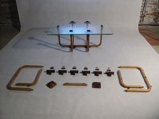 A glass-topped table sitting next to the same, deconstructed, model