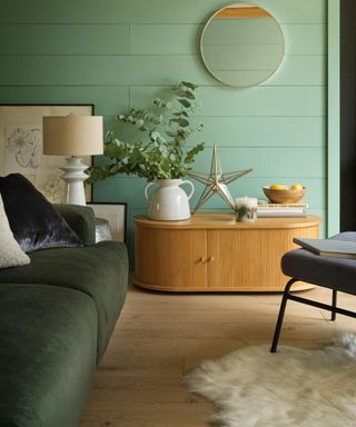 Green living room lounge with green wall paint and gold round mirror idea
