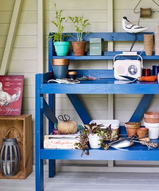 wooden shed with blue table and potted plants