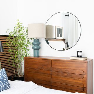 Round mirror above chest of drawers in bedroom
