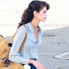 First look at Kaia Gerber in Ryan Murphy's new 80s thriller, "The Shards." Kaia showed off an uncanny resemblance to her mom, Cindy Crawford, with a classic 80s hairstyle and wardrobe. She's wearing a silk blue blouse, bootcut jeans, and Ugg Classic Micro mules.