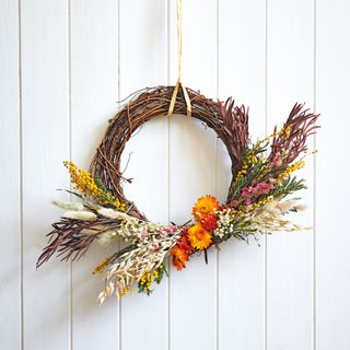 Dried flower wreath hanging on white panelled wall