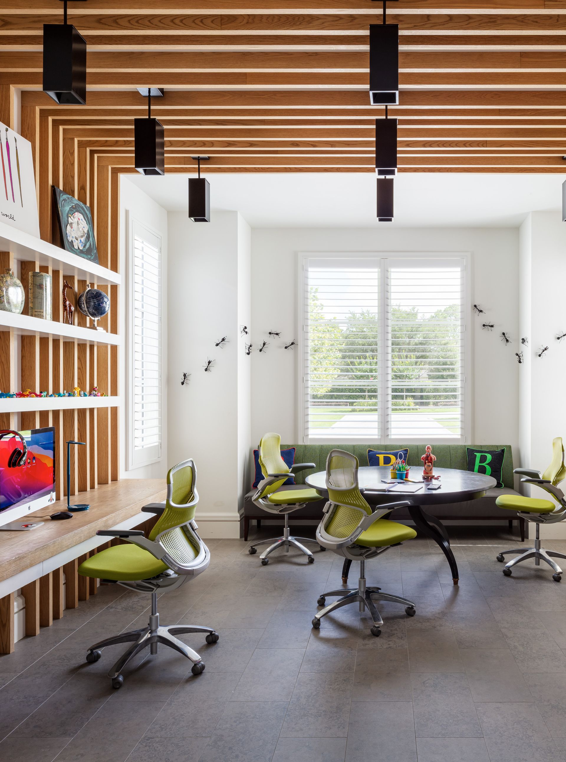 A home office space with contemporary wooden beams, a built in desk, and a green sofa in the window alcove