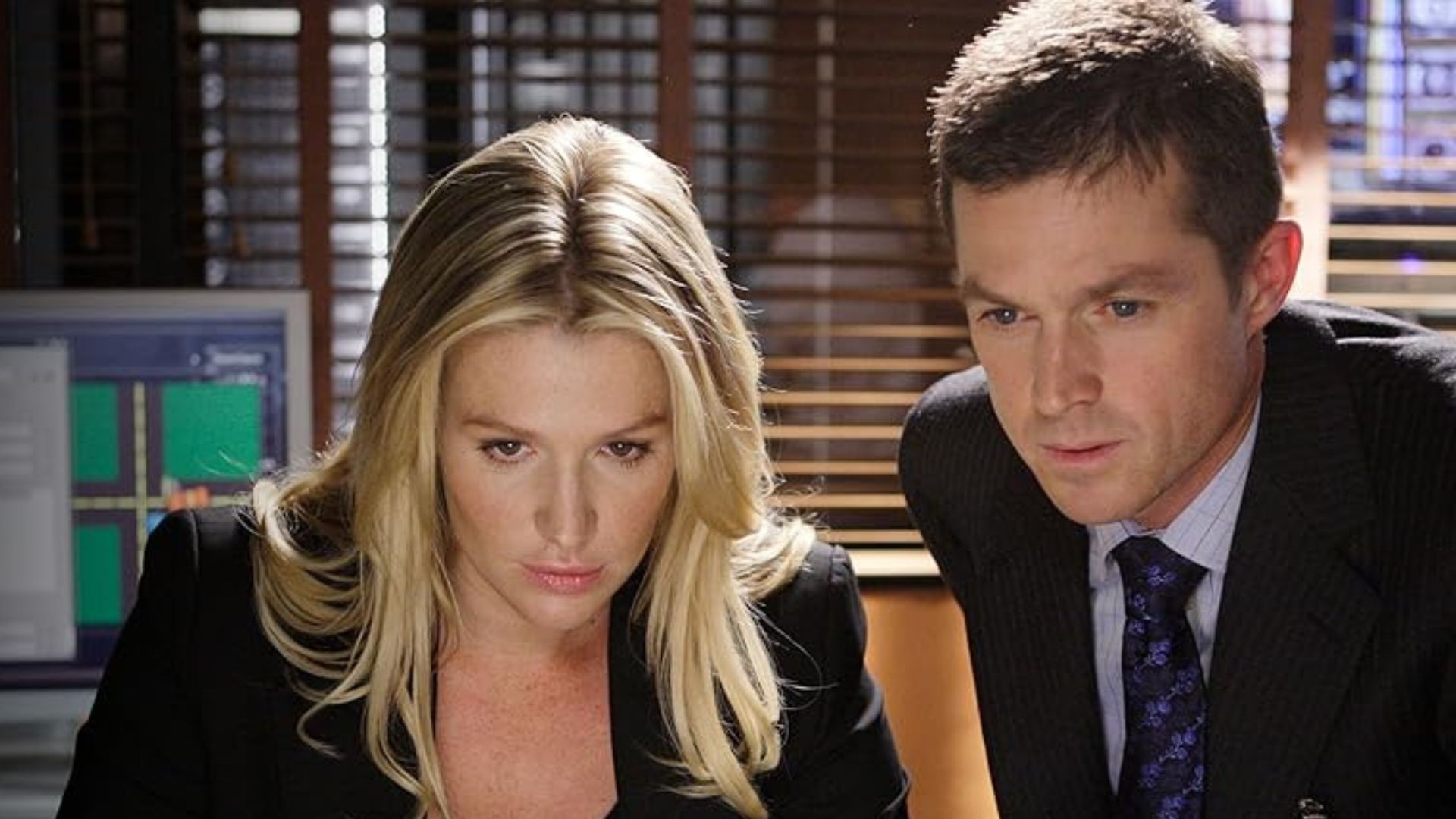 Poppy Montgomery and Eric Close look at a computer screen in an office