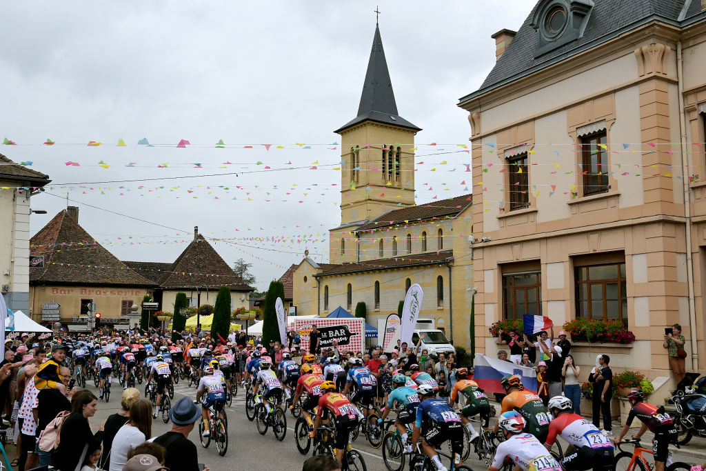 SAINT VULBAS, FRANCE - JULY 03: A general view of the peloton passing through Montagnieu village while fans cheer during the 111th Tour de France 2024, Stage 5 a 177.4km stage from Saint-Jean-de-Maurienne to Saint Vulbas / #UCIWT / on July 03, 2024 in Saint Vulbas, France. (Photo by Tim de Waele/Getty Images)