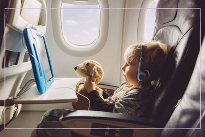 A young boy looking at a tablet while sat on a plane