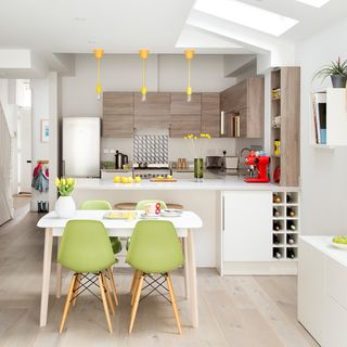 kitchen room with wooden flooring and white table with green chairs