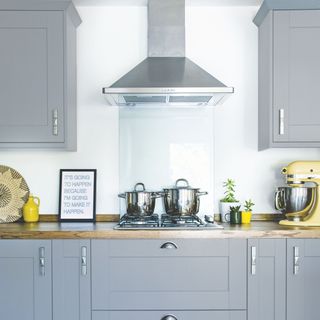 Kitchen with grey cabinets and a wooden worktop, with a gas hob and a glass splashback