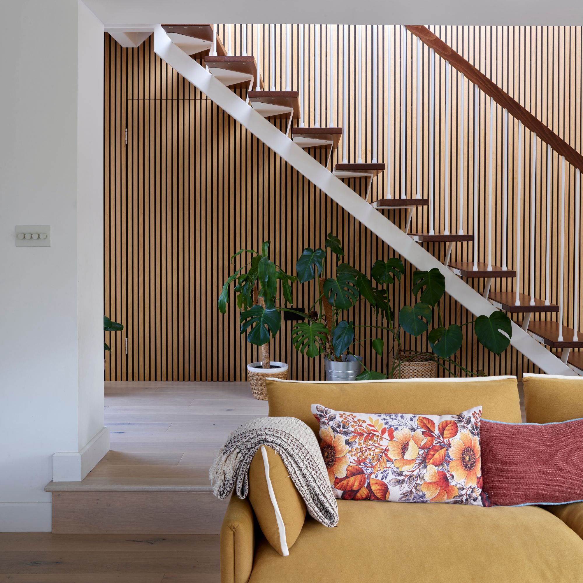 Living room in front of wooden staircase with wooden slatting on the wall