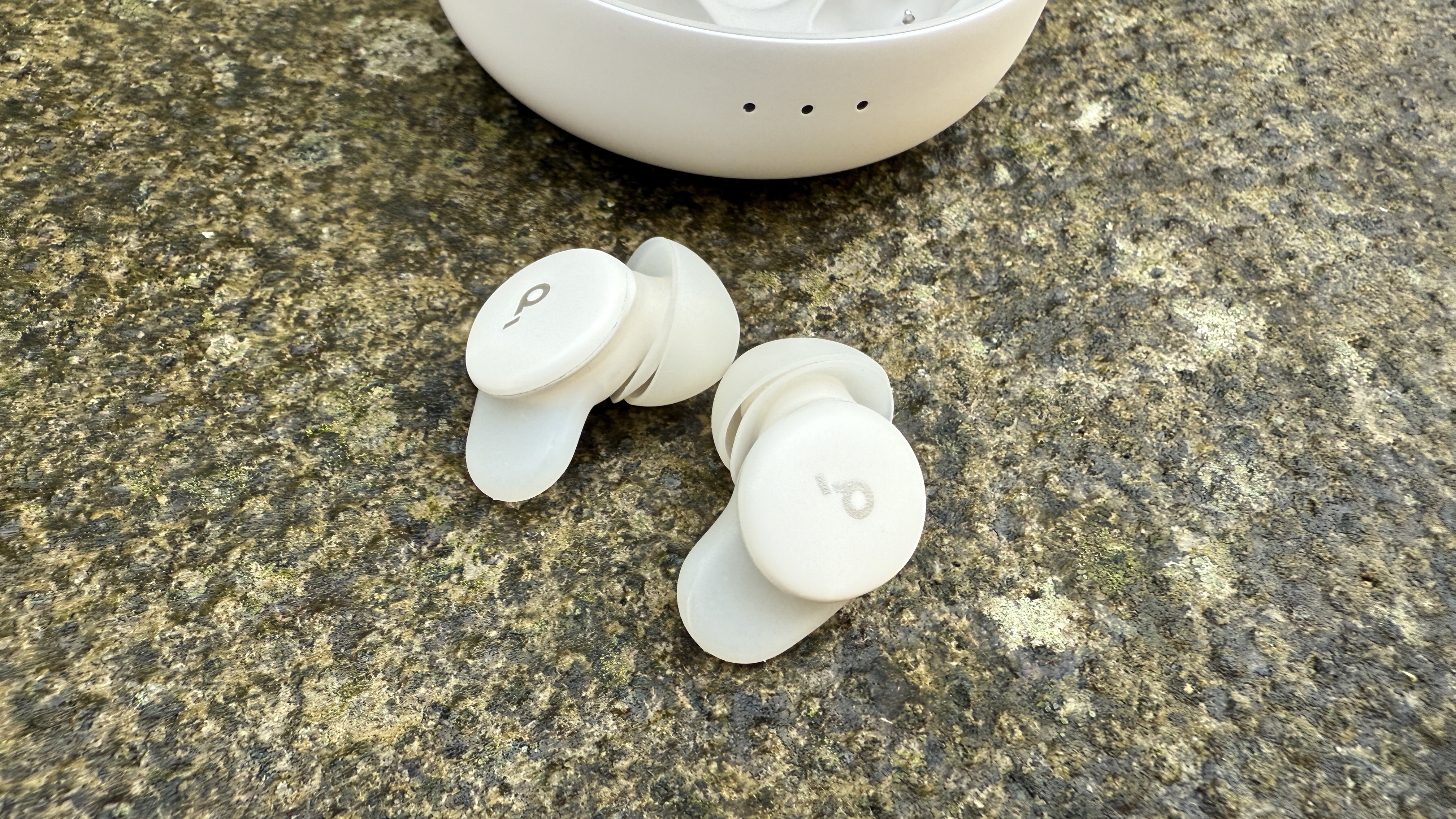 The Soundcore Sleep A30 earbuds on a concrete surface