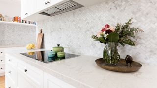 White tiles laid in a herringbone style in a white kitchen