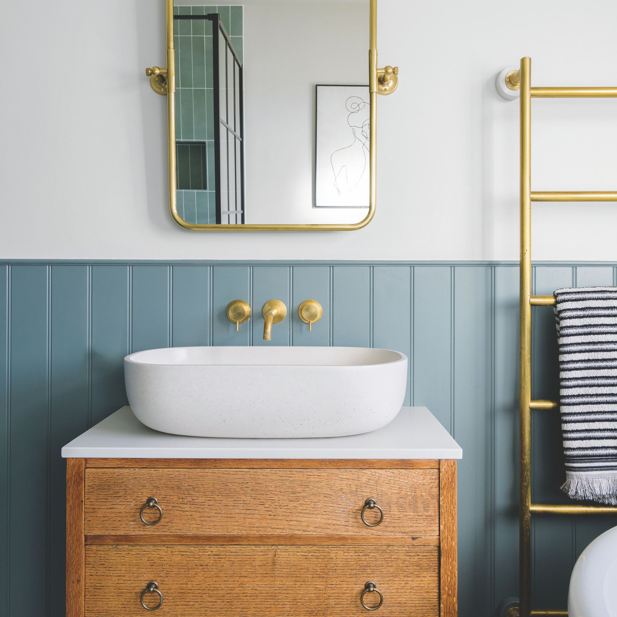 White painted bathroom with blue panelling and a wooden vanity unit with a sink on top