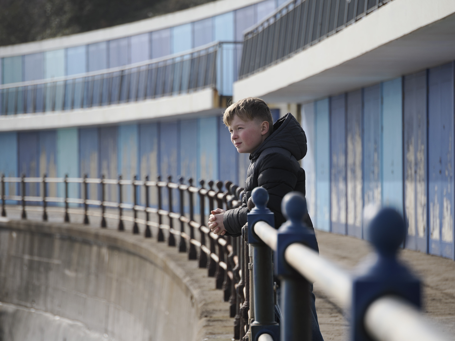 OM System OM-3 sample photos: portrait of boy in coat by beach huts