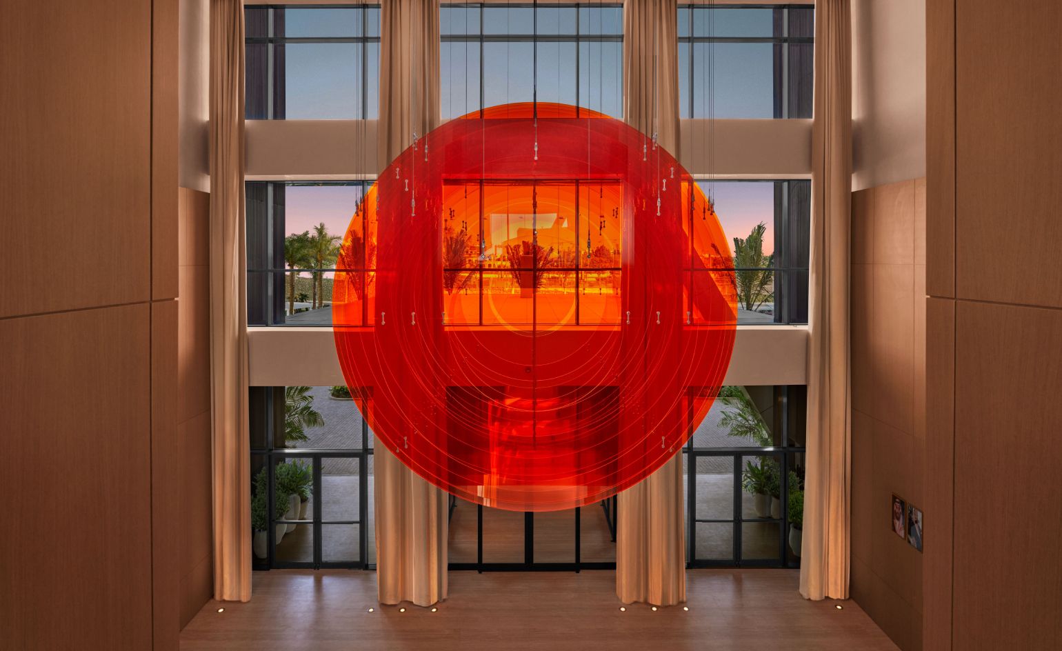 orange circular light in front of hotel window with palms outside