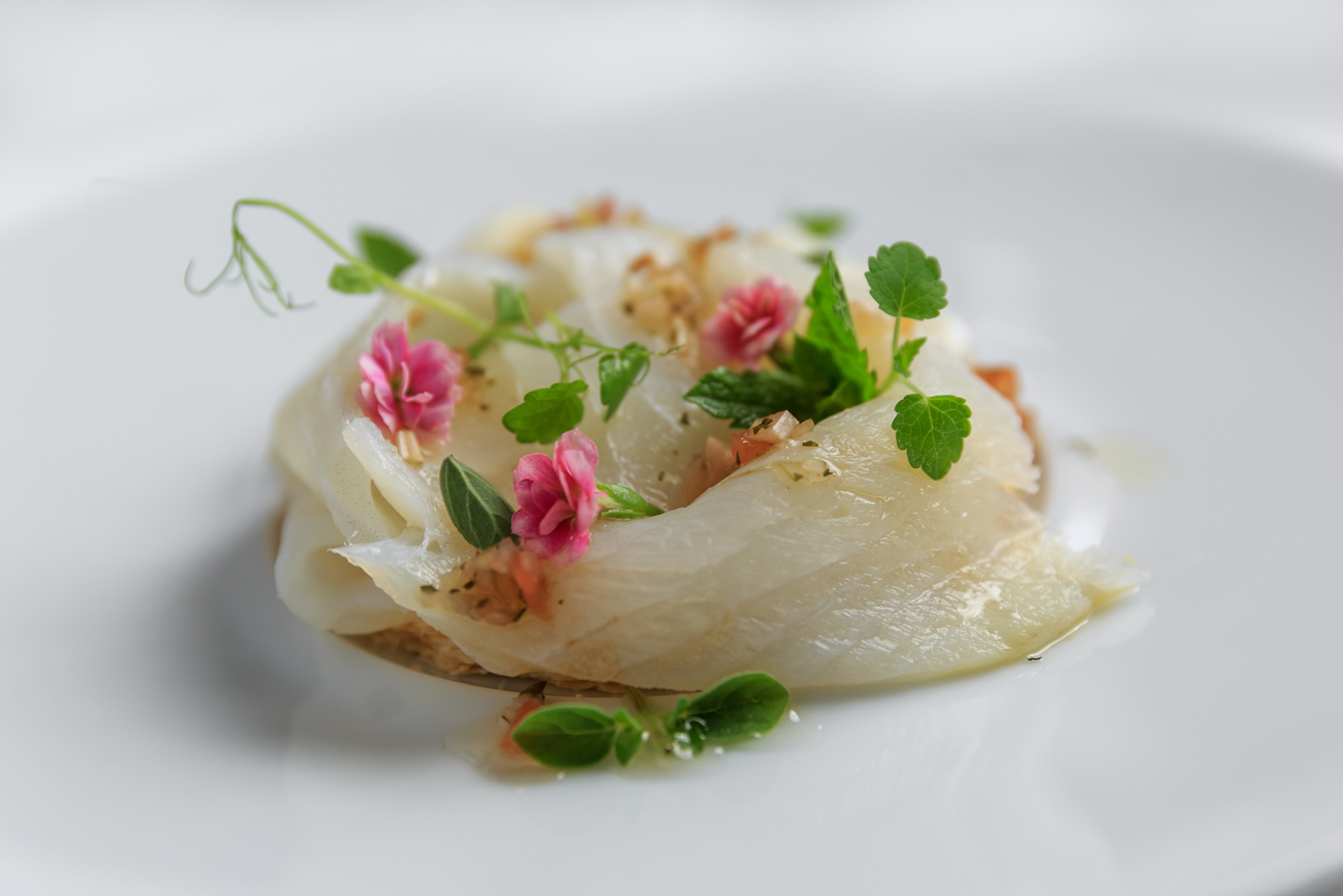 A fish dish with herbs and edible flowers