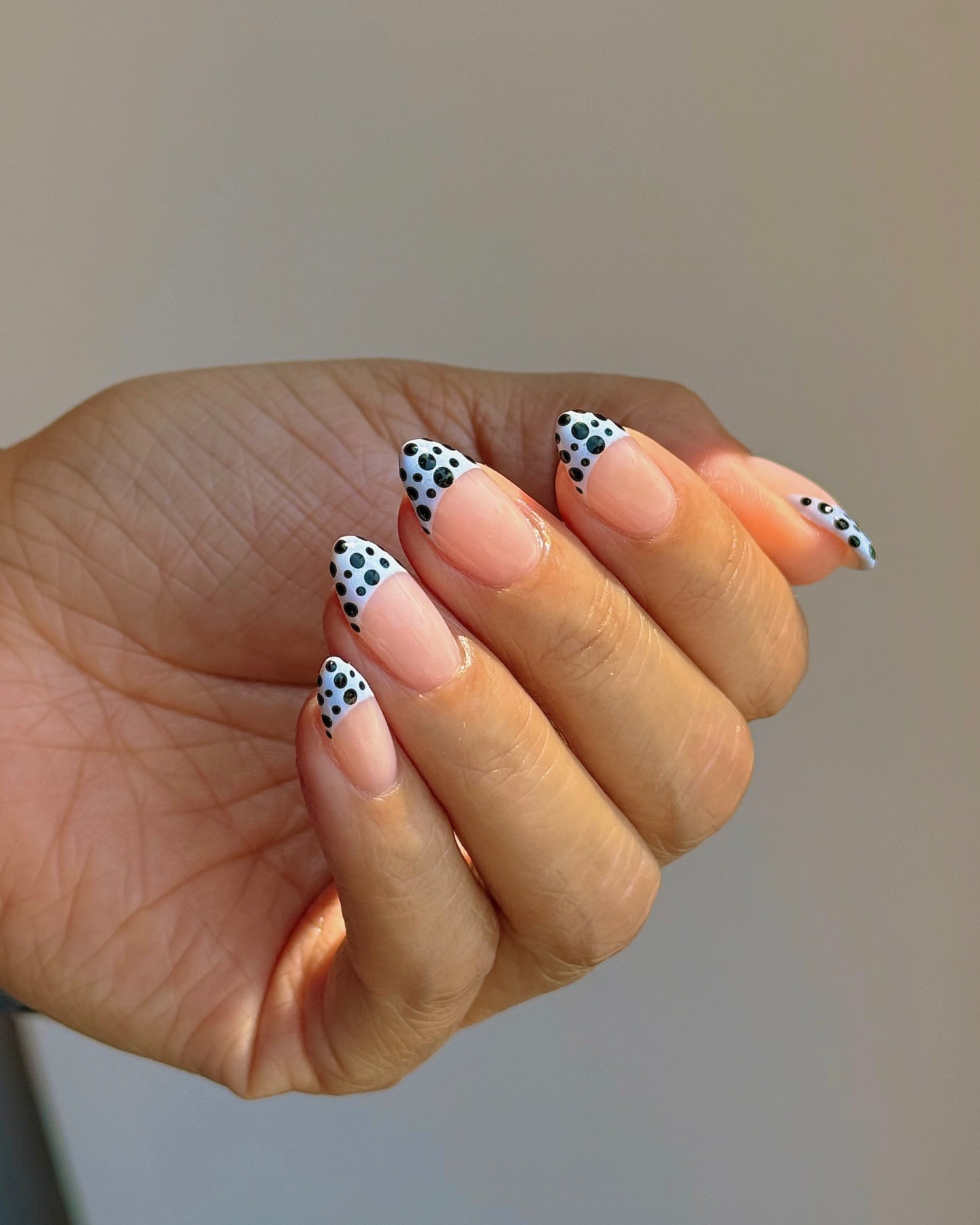 A blue and black polka dot French tip manicure