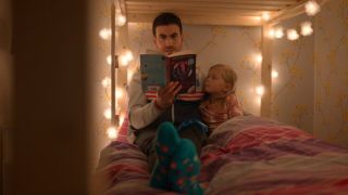 Roy reading a book to Pheobe in her bunk bed.