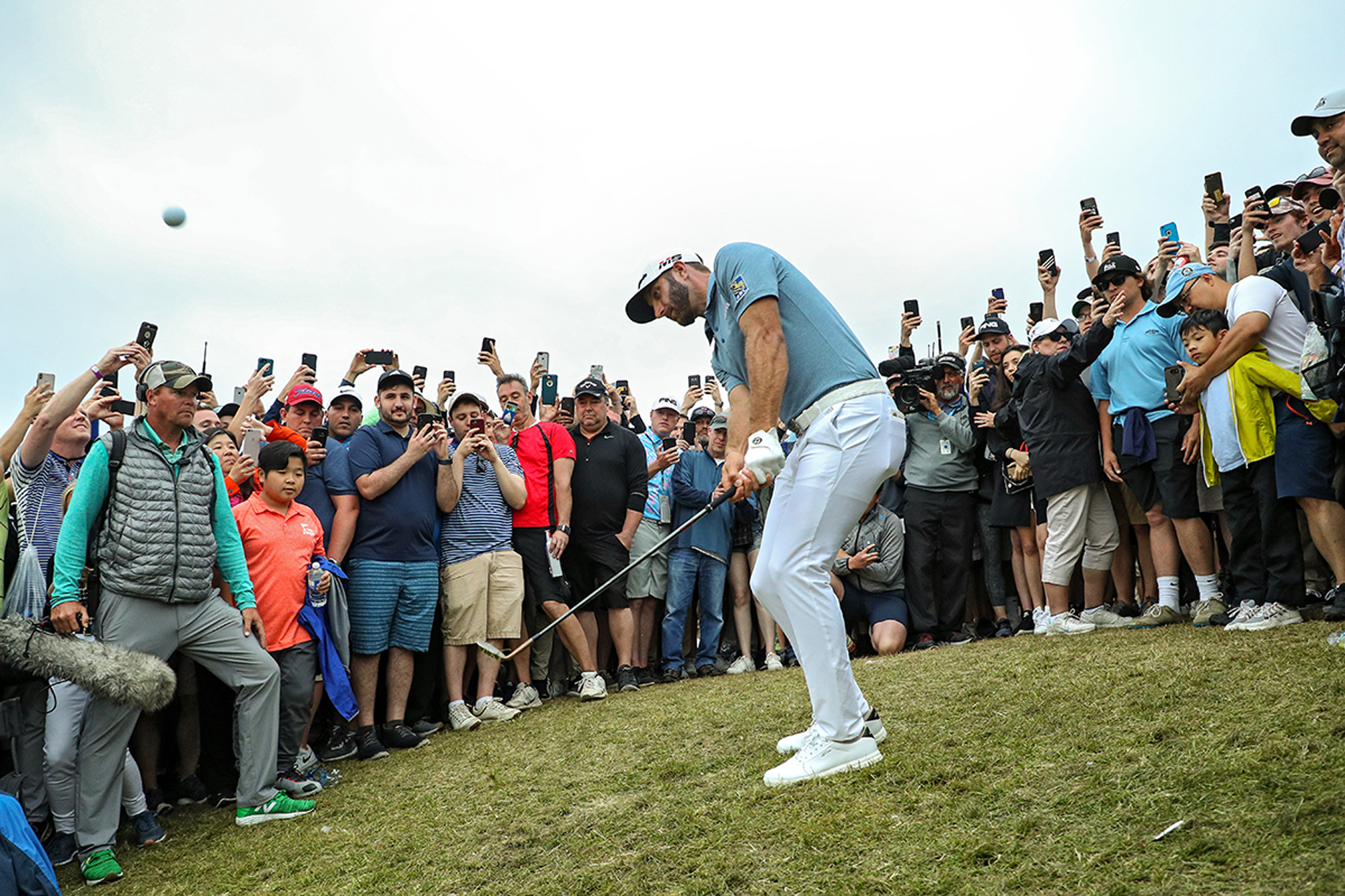 Dustin Johnson hitting a shot in front of a cheering crowd at the PGA Championship when held at Bethpage Black in 2018
