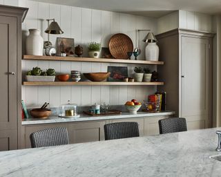 An example of small kitchen ideas showing open shelving units storing crockery, vases and pots in between neutral cabinets