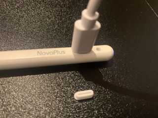A white NovaPlus A8 Duo stylus being held in a hand and used on an iPad