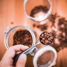 A hand holding coffee beans in a spoon