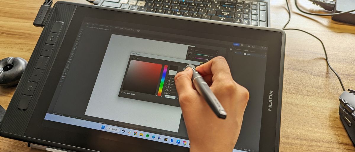 Huion Kamvas Pro 13 2.5K graphics / drawing tablet being used on a wooden table in an office space in the daytime.