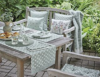outdoor dining table dressed with cottage style furnishings in a small garden