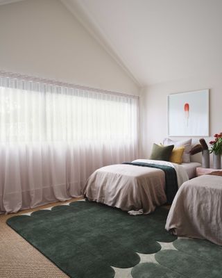 A bedroom with a jute carpet and a green rug placed over it