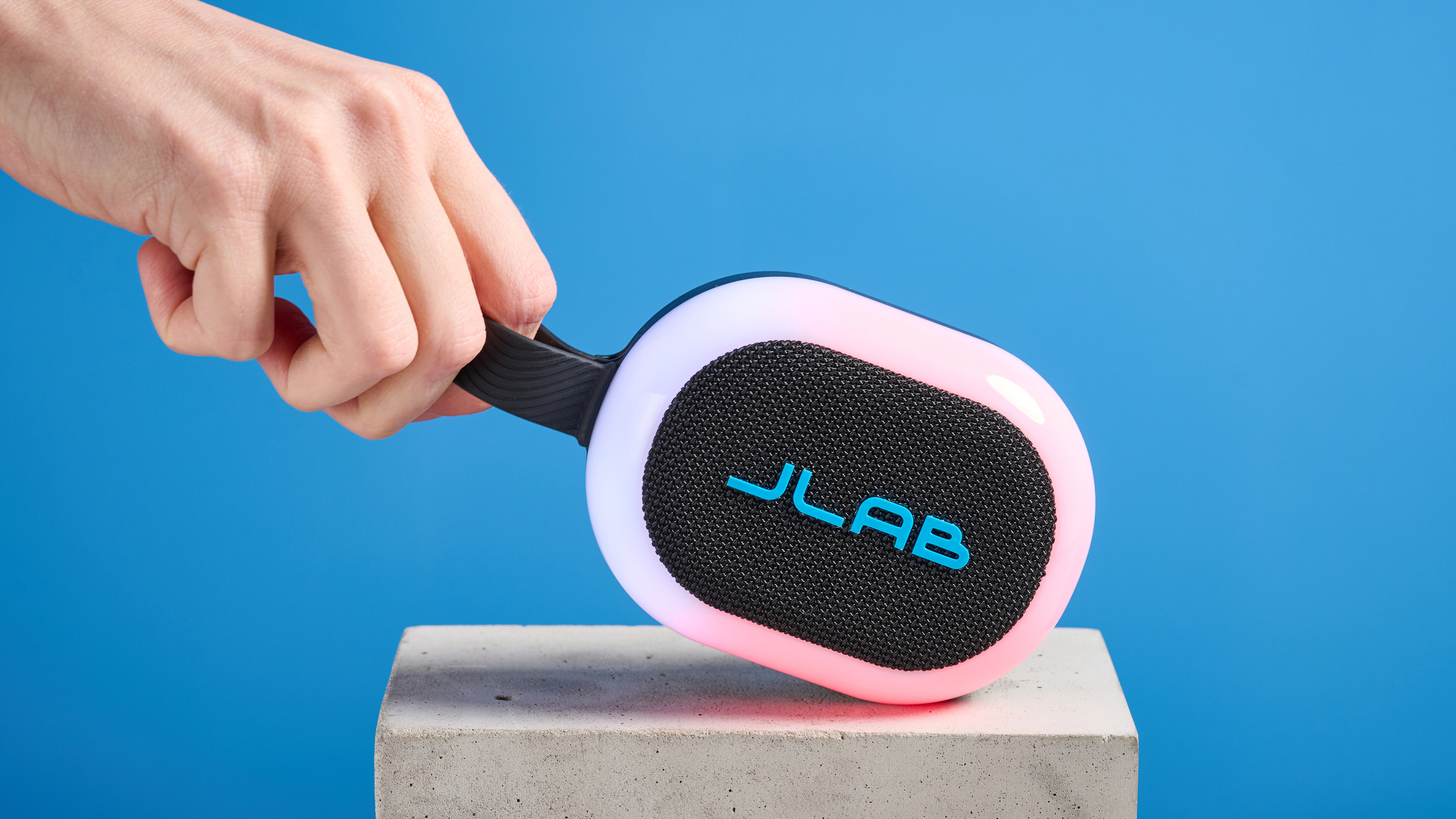 JLab Pop Party portable Bluetooth speaker with RGB lighting photographed on a blue background. 