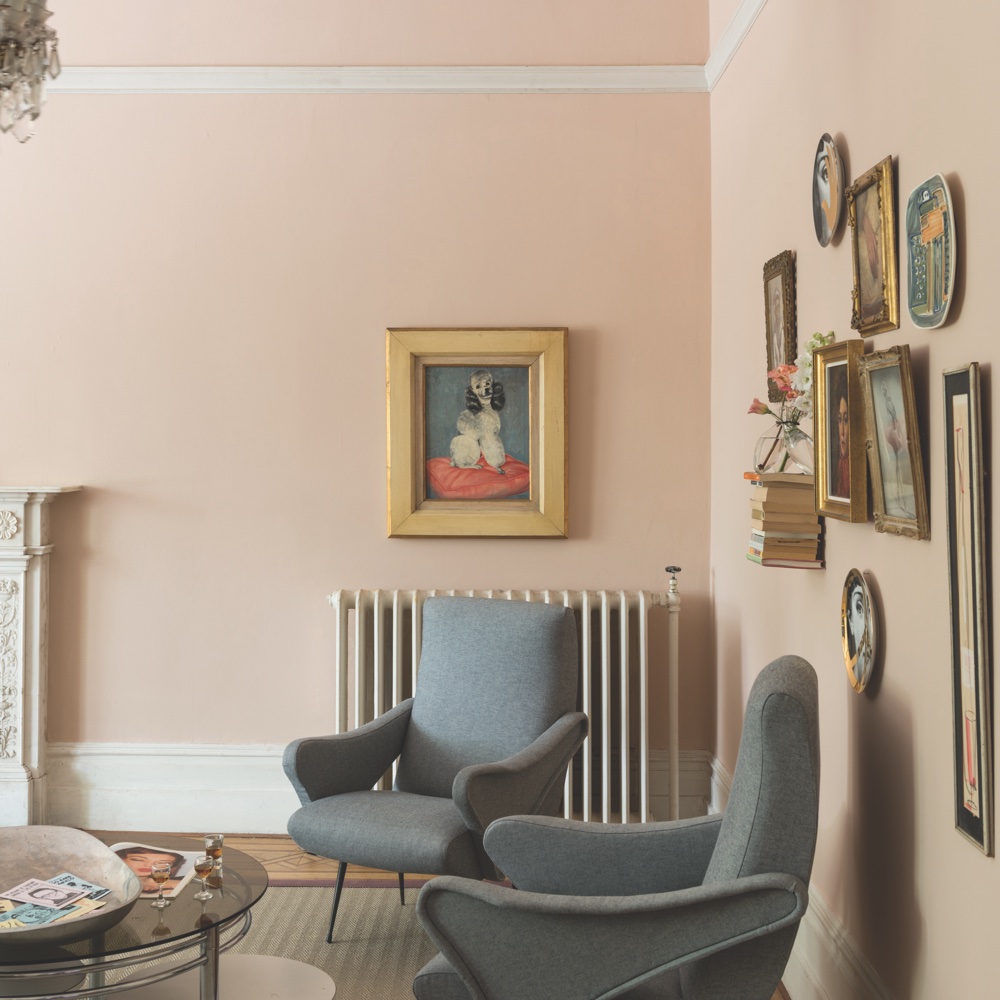 living area with pink wall and grey armchair and picture frame