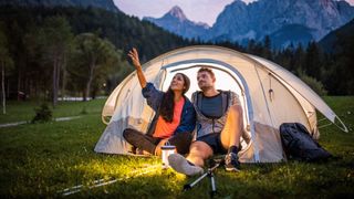 Couple sitting in tent in mountains in the evening
