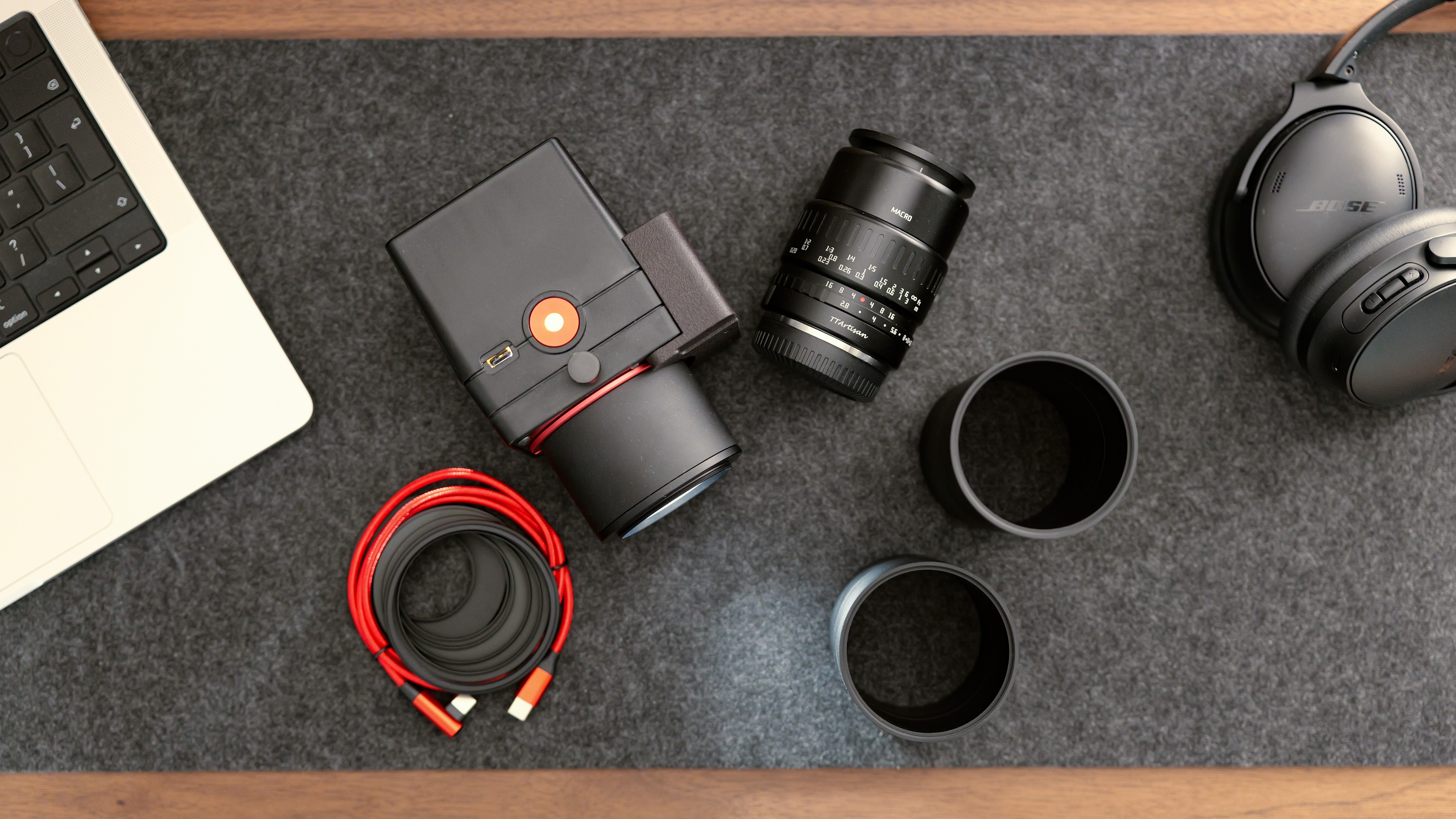 A flat lay of the Valoi easy35 V2 film scanning setup, with a macro lens, adapter tubes, cables, laptop, and headphones on a desk.